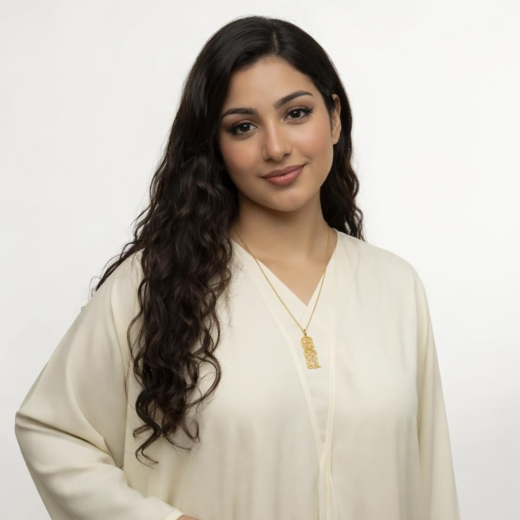 Woman wearing a cream abaya with a gold necklace saying verily with hardship comes ease on a plain background