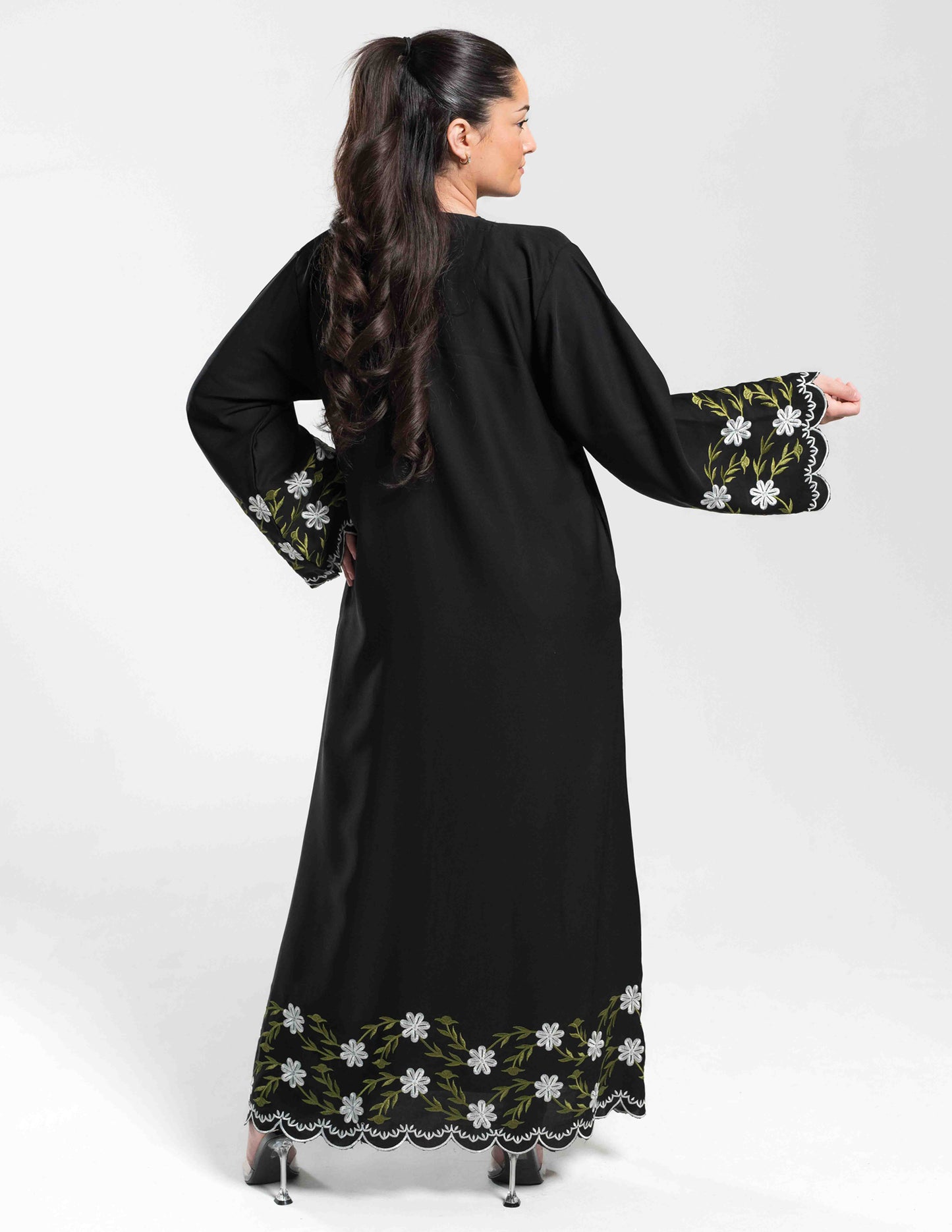 A woman wearing a Hadiqa black floral abaya showing the back view without a hijab, highlighting embroidery and overall fit.