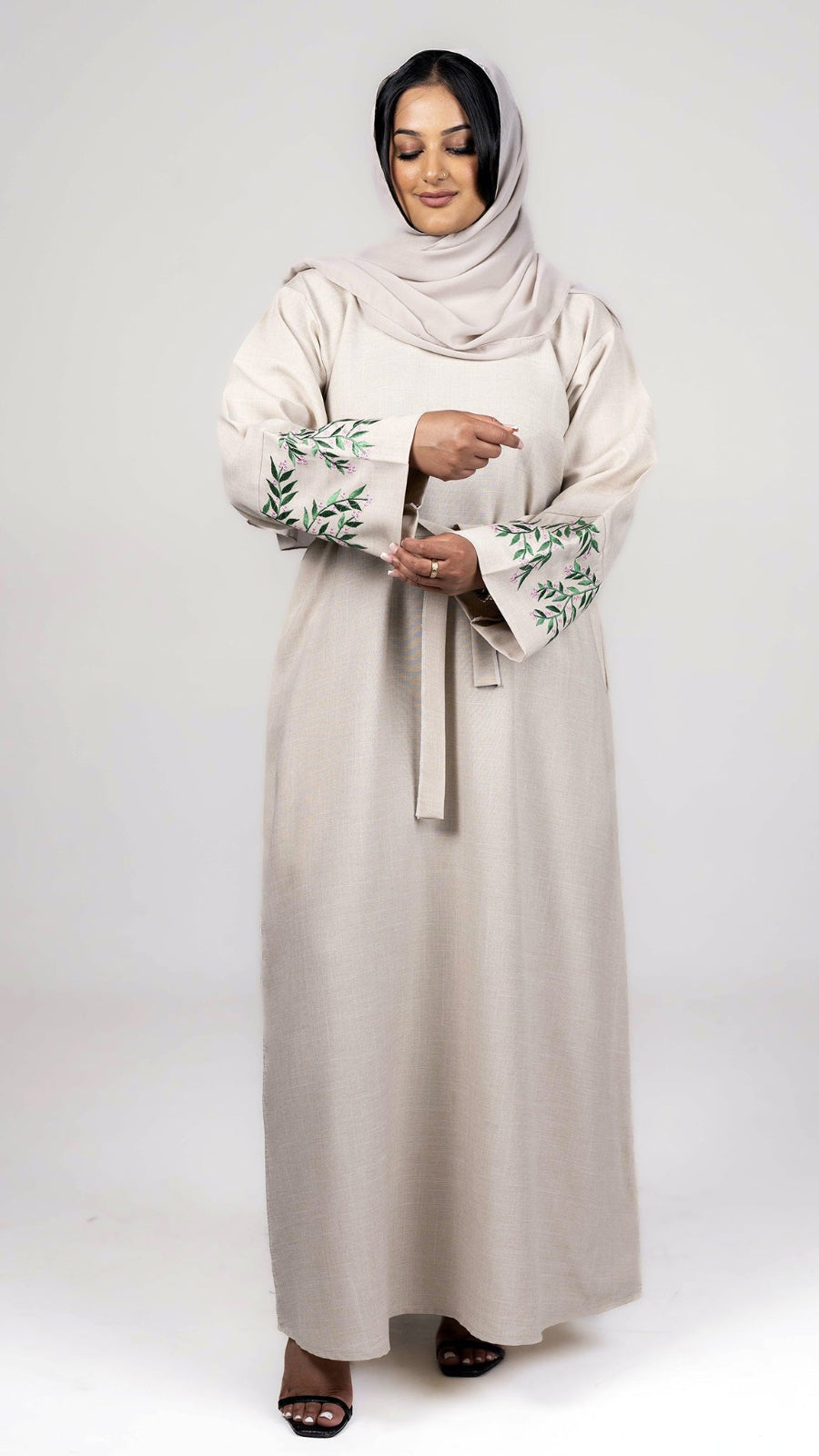 Beige linen closed abaya showing detailed front sleeve design and stitching craftsmanship.