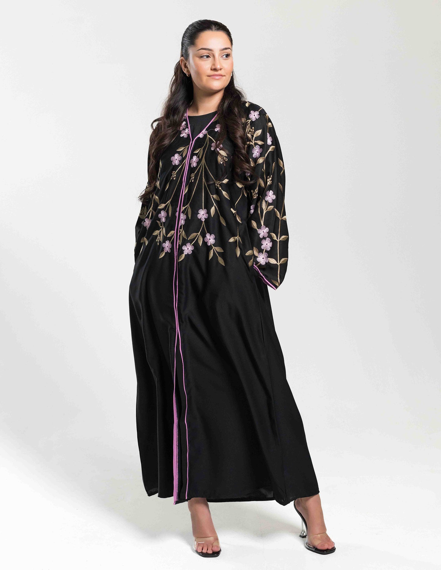 A woman wearing a black floral embroidered open 'Monsoon' Abaya with hand-embroidered detailing, paired with a matching hijab and belt.