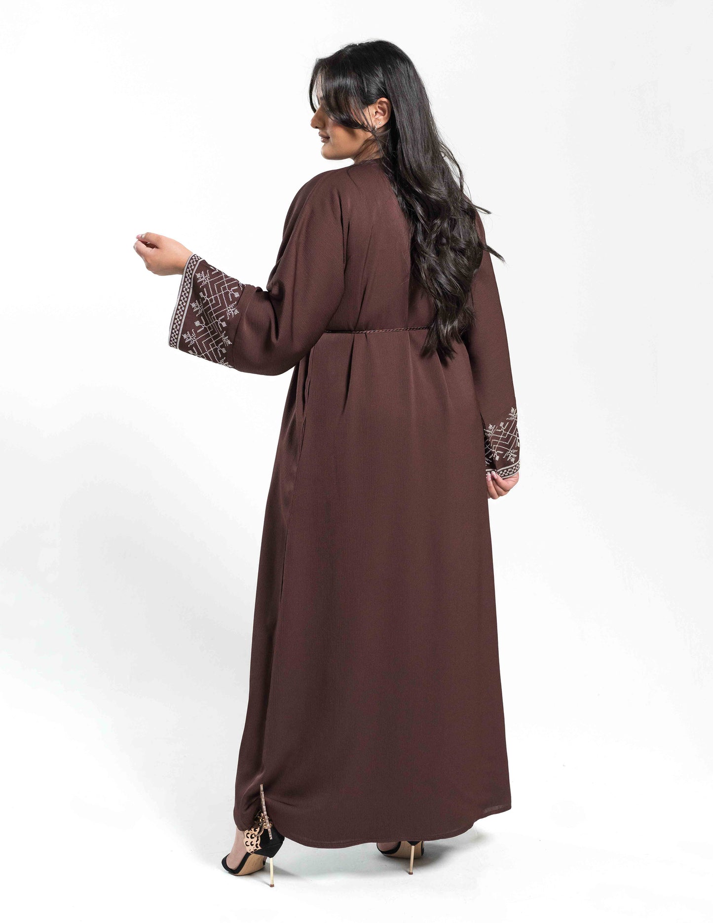 A woman wearing a brown essential open abaya showing the full back view and flowing fabric details.