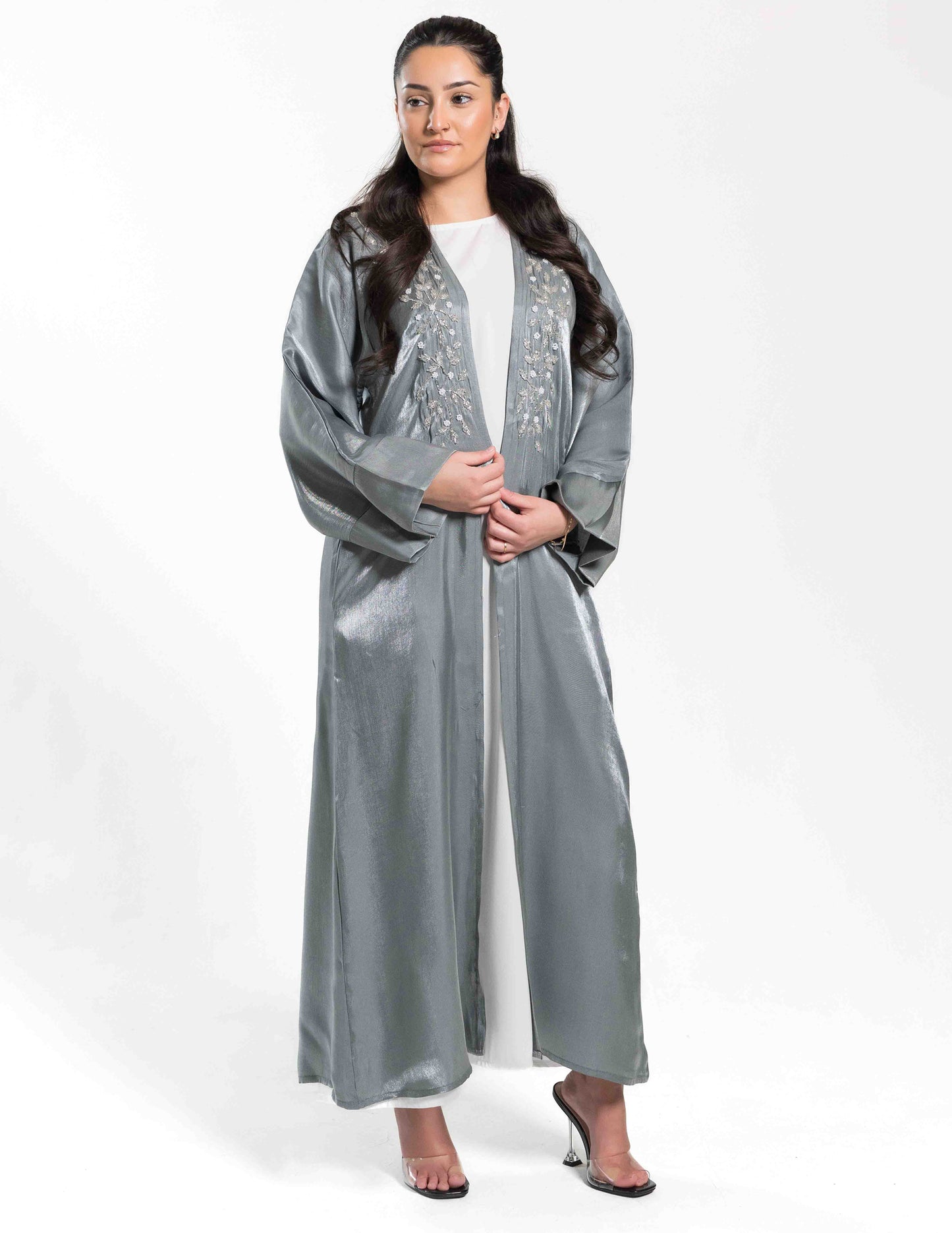 A woman wearing a Marinaa abaya showing the front-left angle, highlighting fabric drape and design details.